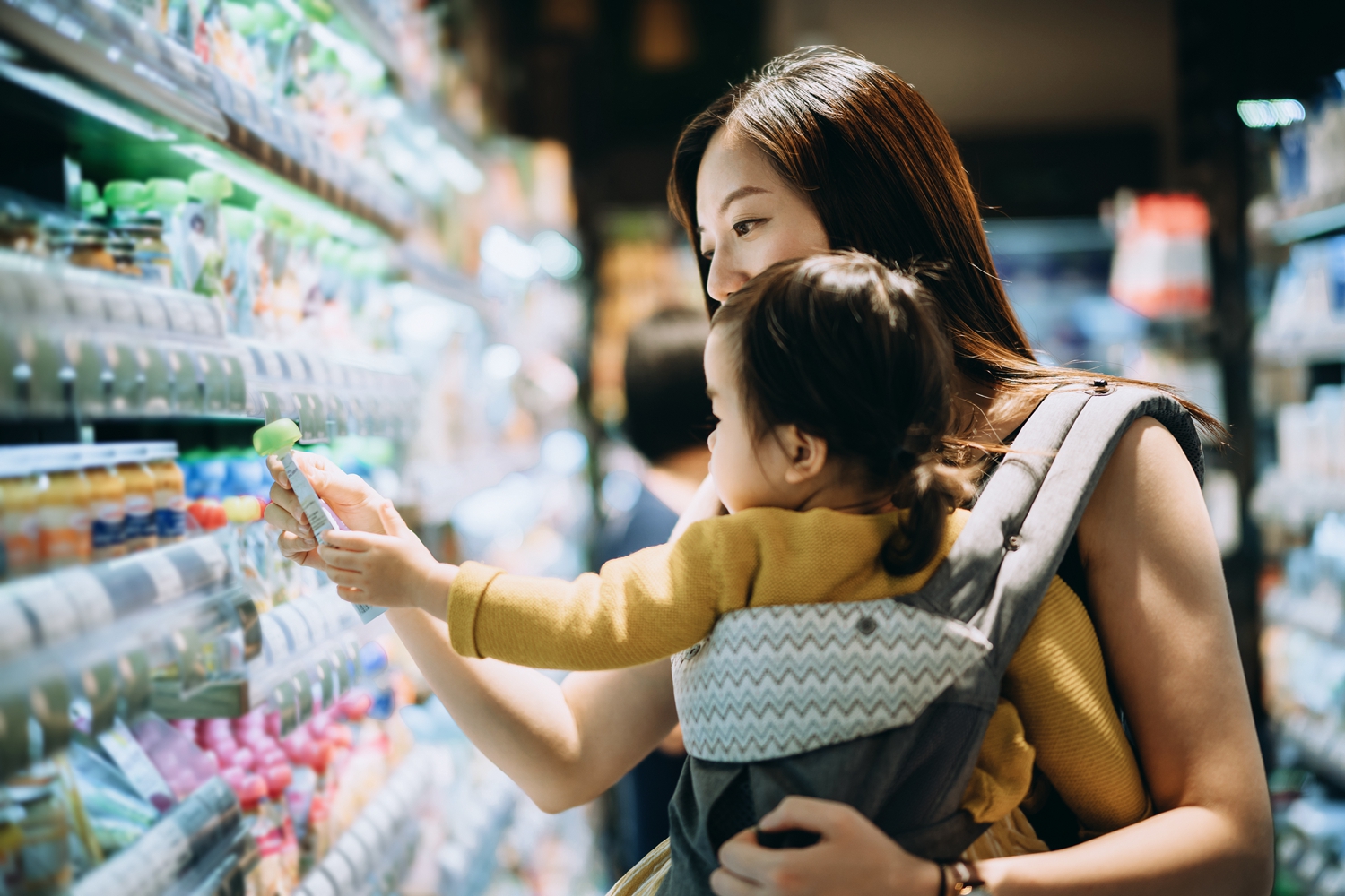 Young Asian mother grocery shopping with little daughter