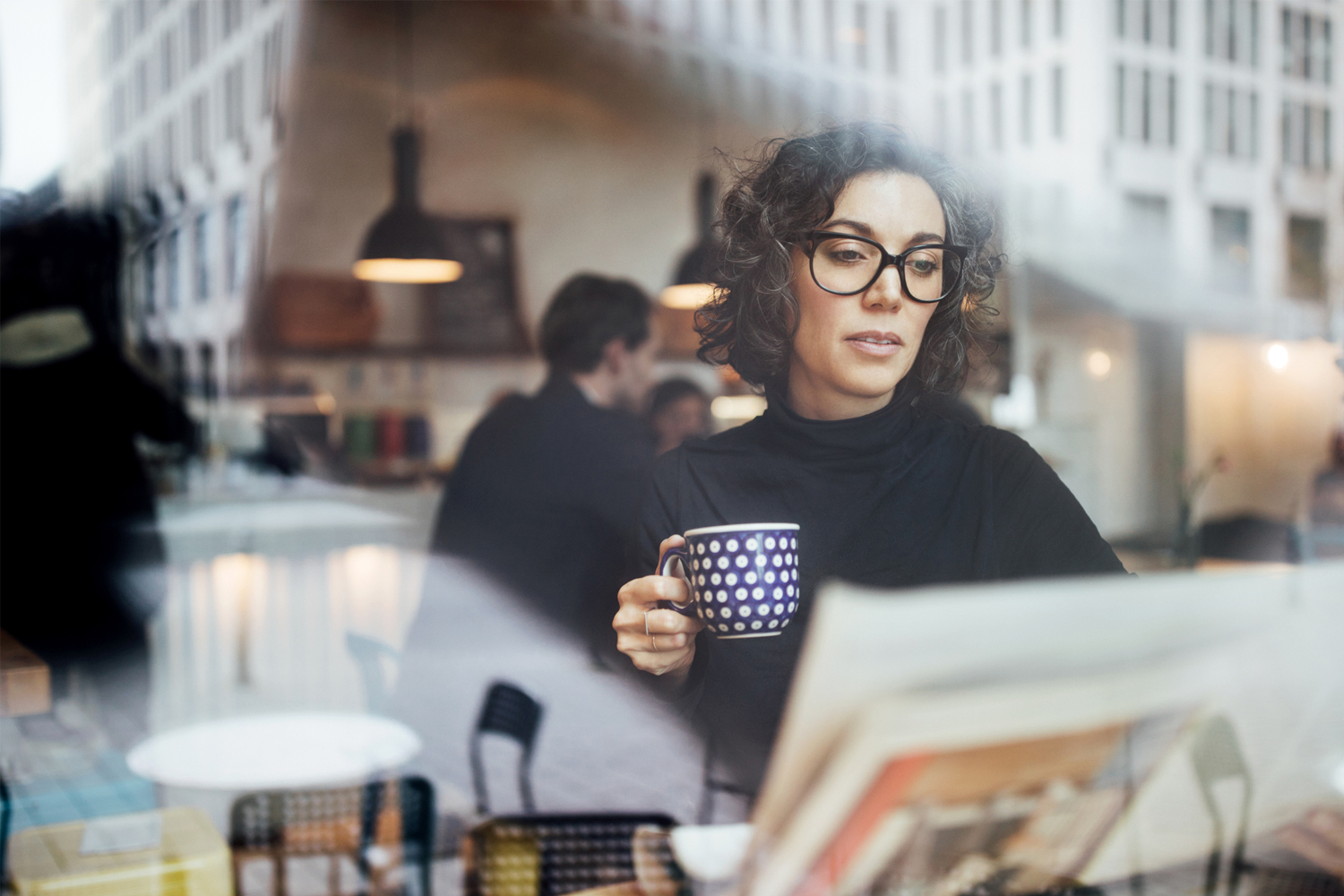 mujer con taza leyendo el periódico