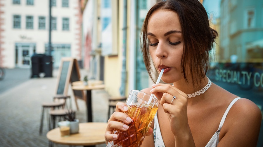 Une femme boit un thé glacé en terrasse
