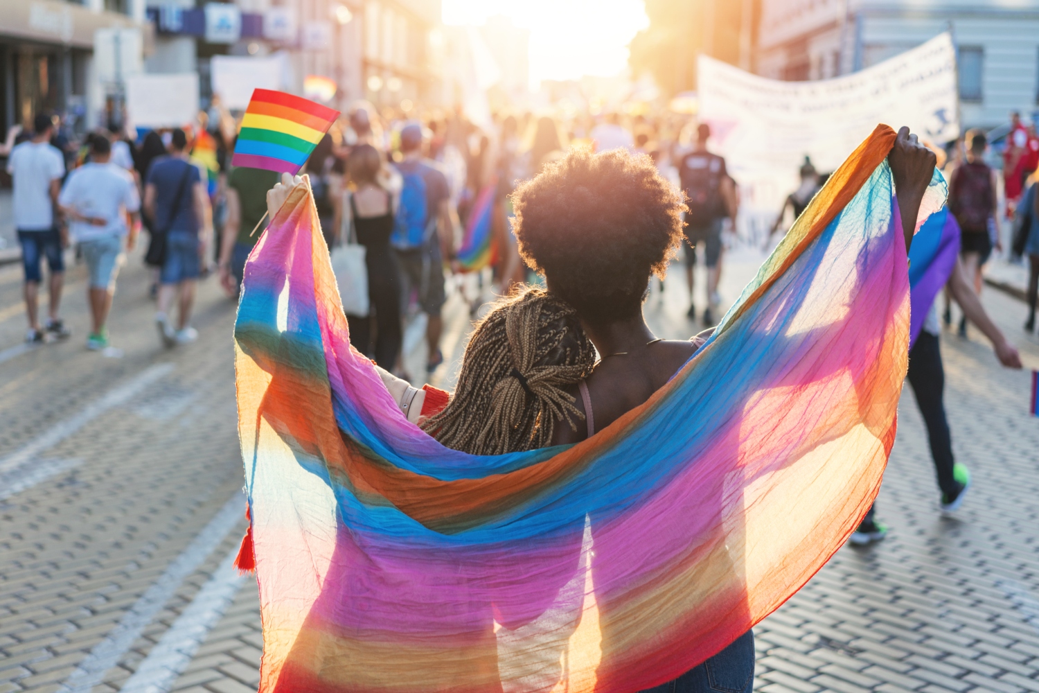 Two people walking down the street holding a Pride flag.
