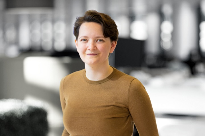 A photograph of the head and shoulders of Megan, wearing a brown jumper.