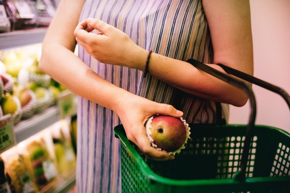 Shopper putting an apple into a shopping basket